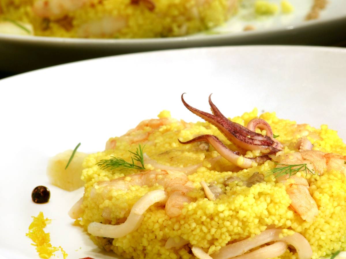 Biały talerz z portawą z kuskusu, udekorowany piórkami warzyw. Ilustracja do artykułu: "Ile kuskusu na 1 osobę potrzeba, aby przygotować idealne danie?"