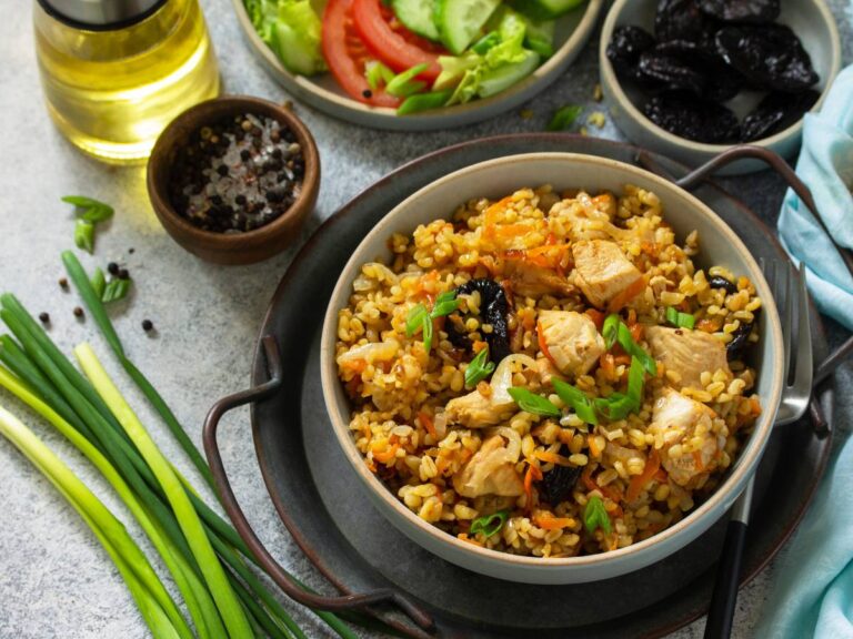 Na pierwszym planie miska apetycznej potrawy z kaszą, z tyłu miska z warzywami i ook niej dwie małe salaterki z dodatkami. Ilustracja do artykułu: "Analizujemy, czy kasza bulgur dla cukrzyków to dobry wybór"