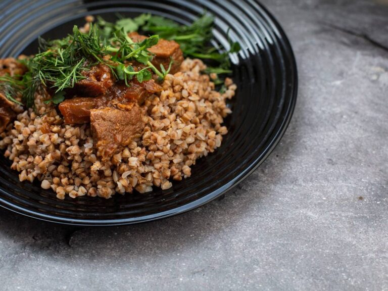 Ugotowana kasza gryczana na ciemnym talerzu. Ilustracja do artykułu "Odkryj 6 przepisów na to, co zrobić z ugotowanej kaszy gryczanej bez marnowania".