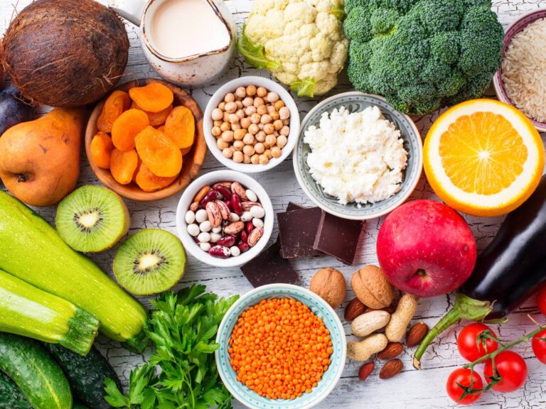 Różne produkty żywnościowe ułożone na stole i w miseczkach: kasze, warzywa, mięso, nabiał. Ilustracja do artykułu: "Poznaj indeks glikemiczny 8 rodzajów kasz, od najmniejszego do najwyższego"