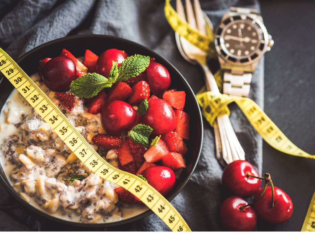 Miska z kaszą i warzywami pod centymetrem i obok sztućce, związane miarką krawiecką. Ilustracja do artykułu:"Odkryj prawdę, czy kasza kuskus idzie w parze z odchudzaniem"