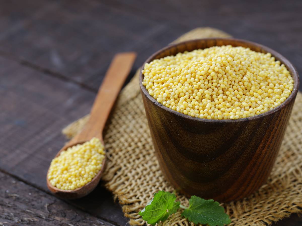 Brązowy kubełek z suchą kaszą i drewniana łyżka obok. Ilustracja do artykułu "Odkryj, która kasza jest lekkostrawna i idealna dla Twojego żołądka"