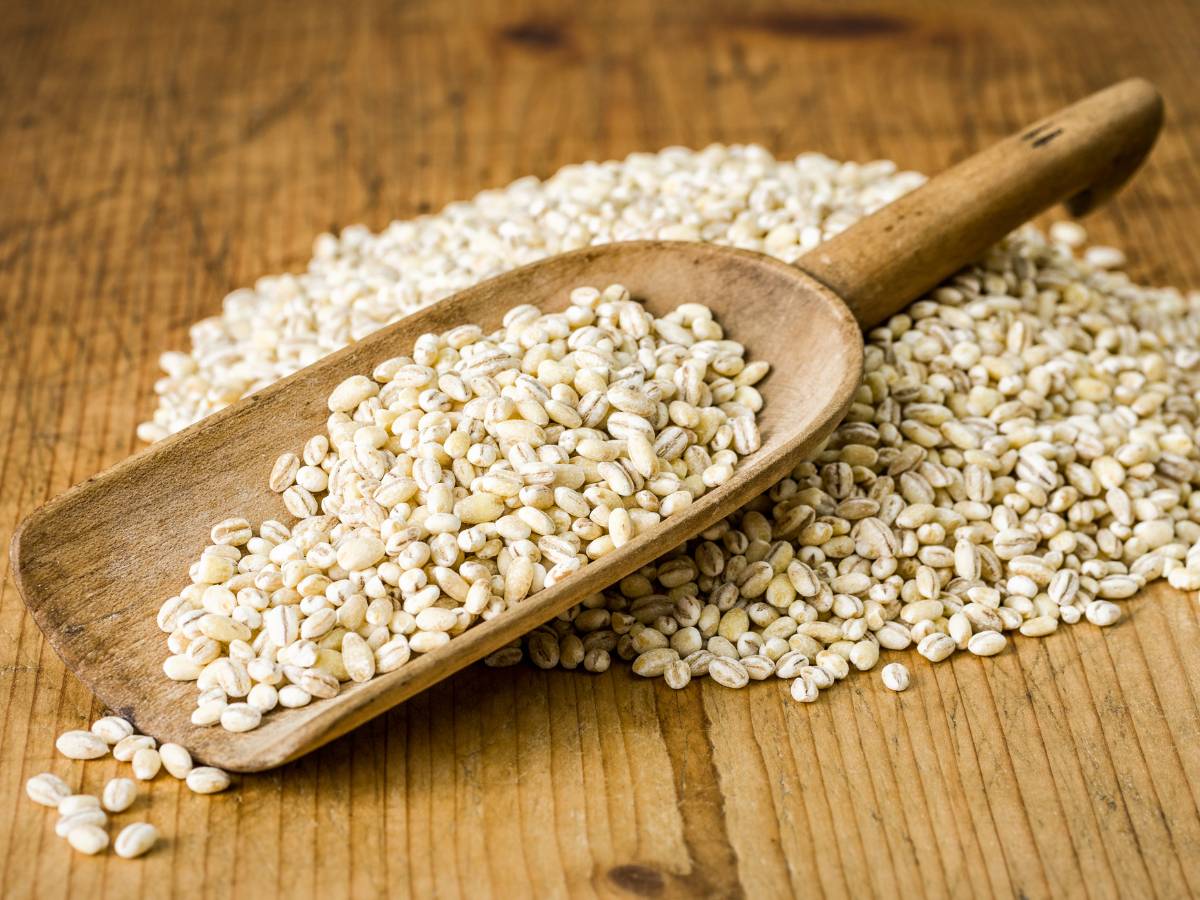 Łopatka drewniana w rozsypanej kaszy pęczak. Ilustracja do artykułu:"Sprawdź, czy dotyczą Ciebie przeciwwskazania do jedzenia kaszy pęczak"