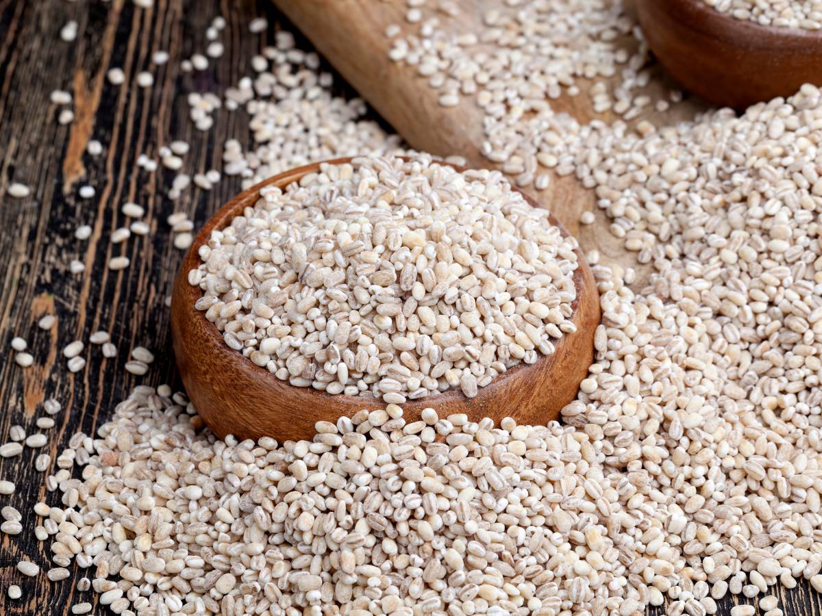 Blat stołu i miska drewniana zasypane suchą kaszą pęczak. Ilustracja do artykułu: Odkryj, z czego jest pęczak i poznaj historię tego superfoodu