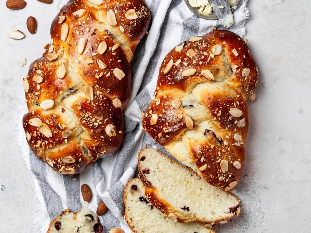 Upieczone chałki na obrusie, z odkrojonymi kromkami.